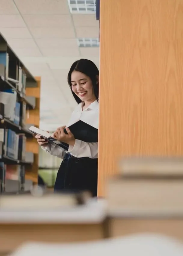 Học sinh mỉm cười cầm sách trong lớp học