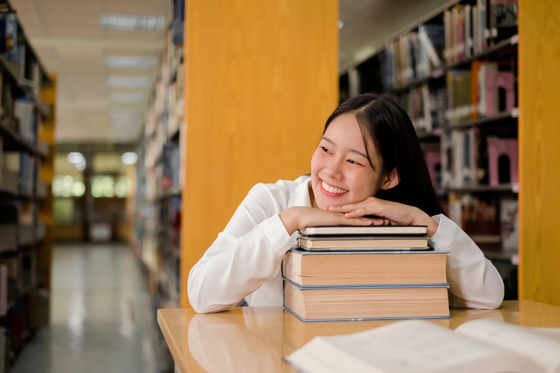 A student reading among the shelves in the library